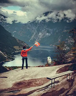 Visit Prints: Female tourist enjoying scenic view over fjord Geirangerfjorden from Flydalsjuvet viewpoint
