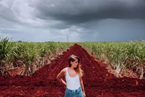 Heaven Prints: Female traveler in casual wear standing on crossroad with brown soil among green tropical plants under grey cloudy