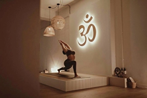 Equilibrium Prints: Female yoga instructor with arms raised bending while practicing by Om symbol