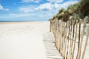 Coast Prints: A fence lines part of the beautiful beach at Holkham on the North Norfolk coast protecting the sand dunes