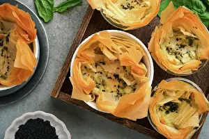 Cheese Prints: Filo-Pasteten mit weichem Feta-Käse und Spinat in Keramik-Formen auf alten grauen Tisch Hintergrund