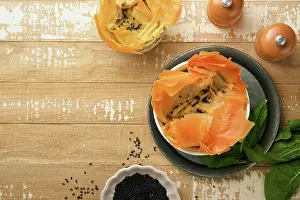 Cheese Prints: Filo-Pasteten mit weichem Feta-Käse und Spinat in Keramikformen auf alten Holztisch Hintergrund