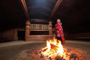 Baby Boomer Prints: A first nations elder dressed in her traditional regalia stands beside a fire in the bighouse in the village of