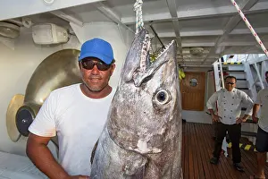 Tuna Prints: A fisherman poses with a dogtooth tuna (Gymnosarda unicolor); Tahiti