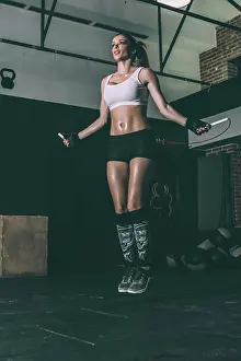 Rope Prints: Fit blonde woman jumping rope training working out in Gym