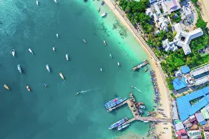Bustling Prints: Flying above busy tropical island port filled with boats and fer