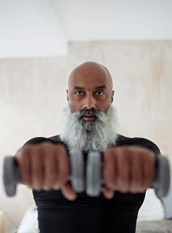 50 54 Years Prints: Focused senior man exercising with dumbbells