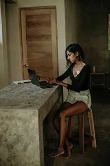Competence Prints: Serious focused youthful ethnic female typing on laptop while sitting at table on table kitchen modern marble
