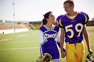 Students Prints: Football player and cheerleader holding hands on football field