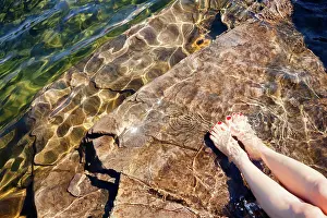 Draussen Prints: Frau taucht ihre Füße in das kristallklare Wasser eines Sees in Norwegen Young woman dipping her feet in a crystal
