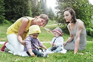 Daughter Prints: Two friend women enjoying a picnic in a beautiful sunny day with their little daughters - Women sitting with little