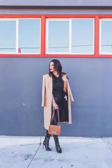 Mixed Prints: Friendly business woman standing in front of gray wall, orange windows