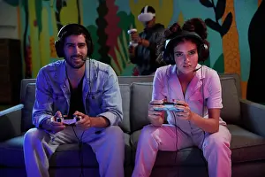 Gaming Prints: Two friends enjoy a competitive video game while another person experiences virtual reality in the background