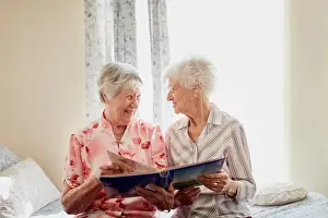 Friends, photo album and happy senior women on bed with memory