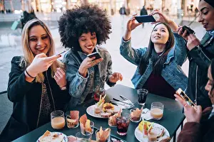 20 To 24 Years Prints: Friends taking photos of their food and drinks at outdoor cafe, Milan, Italy