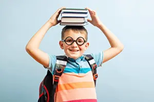 Smart Prints: Funny smiling school boy in glasses holds books on his head on blue background