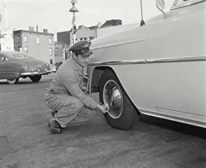 Station Prints: Gas station attendant checking air pressure of a car tire