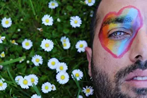 People In Nature Prints: gay man with green eyes and beard lying on a lawn full of daisies