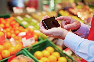 Only One Prints: Germany, Cologne, Mature man using smart phone in supermarket