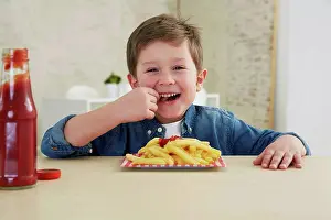 Crisps Prints: Germany, Munich, Boy eating French fries with ketchup