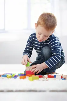 Focusing Prints: Ginger-haired little boy playing at home Ginger-haired little boy playing at home with building cubes