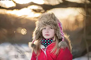Thoughtful Prints: Girl (10) sitting in a tree on the shore of a frozen lake in winter