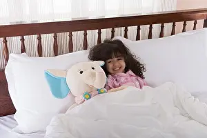 4 5 Years Prints: Girl (3-4) lying on bed by toy, smiling