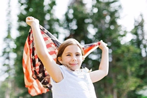 Identity Prints: Girl (8-9) holding us flag in forest
