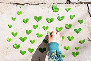 Footway Prints: Girl arranging heart shaped green leaves pattern on cement