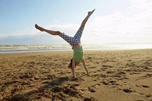 Handstand Prints: Girl doing handstand on beach, Camber Sands, Kent, UK
