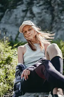 Baseball Cap Prints: a girl in a gray top and a white cap sits on a stone