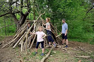 Small Group Prints: Girl holding log while building camp with family in forest