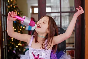 Gradeschooler Prints: A girl with a pink microphone and tutu joyfully sings alone