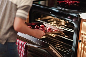 Reality Prints: Girl placing tray of christmas cookies into oven, mid section