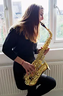 Student Prints: Girl playing saxophone in school uniform; England