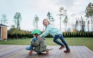 Daughter Prints: girl pushing boy on a skateboard at home in the garden in fall