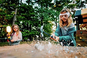 Lighted Prints: Girl smashing lightbulb with hammer on garden table at dusk