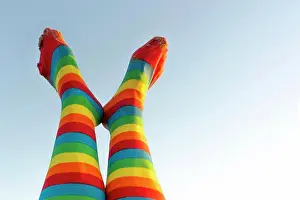 Individuality Prints: girl's feet in a pair of rainbow socks on the blue sky