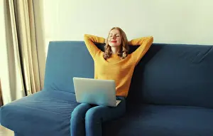 Onlinerechnung Prints: Glückliche junge Frau entspannt sich bei der Arbeit am Laptop