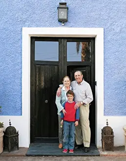 Grandfather Prints: Grandparents and grandson (6-8) standing at front door, portrait