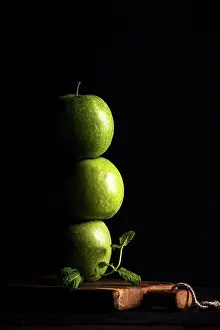 No Body Prints: Green apples making stack or tower with branch of fresh mint on black background