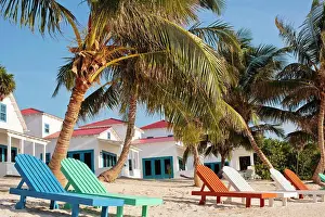 Tranquillity Prints: Group of deck chairs lines up in front of villas on a sandy tropical beach