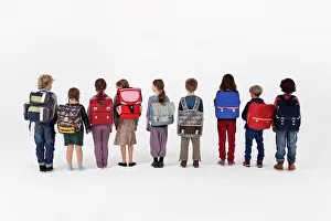 Medium Group Of People Prints: A group of school children wearing backpacks and standing in a row, rear view
