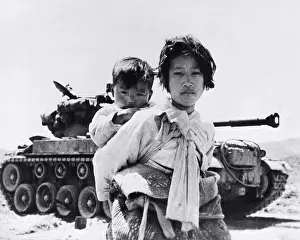 Victim Prints: Haengju, Korea: June 19, 1953 A nine year old Korean refugee girl carrying her small brother trudges past a Patton tank