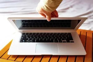 : Hand closing the white laptop.