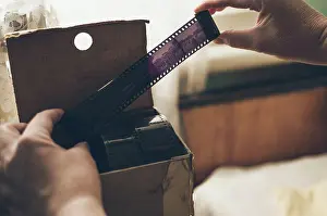 Fourties Prints: Hands hold old photo film over cardboard box