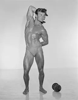 Attractive Prints: Handsome Muscular Young Man Flexes Near Weights c.1956