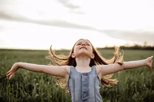 People In Nature Prints: Happy 5 years old girl in a green wheat field with long hair at sunset