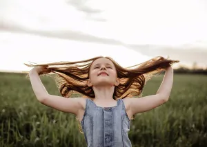 People In Nature Prints: Happy 5 years old girl in a green wheat field with long hair at sunset