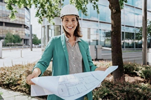 Competence Prints: Happy architect wearing hardhat standing with construction plan